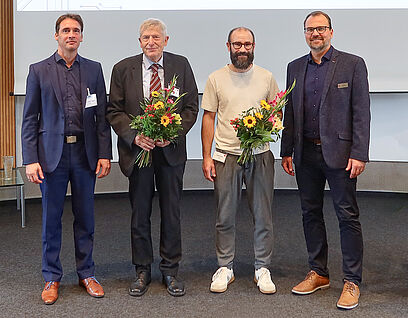 Vier Personen stehen für ein Gruppenfoto nebeneinander und haben Blumensträuße in der Hand