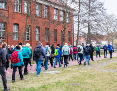 Menschen wandern entlang einer Hauswand