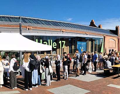 Erstsemester-Studierende in einer Schlange stehend bei der Ausgabe von TH-Wildau-Shirts vor Halle 17