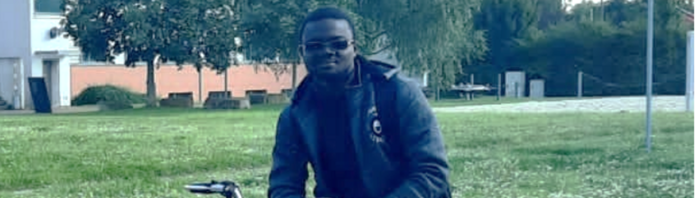 Ein Student auf einem Fahrrad vor einem Universitätsgebäude auf dem Campusgelände.