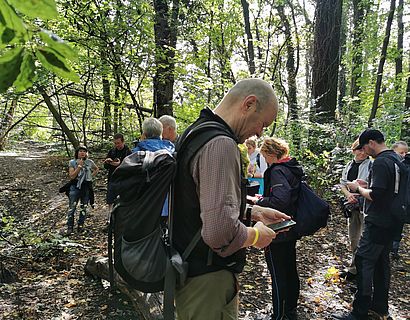 Wander/-innen bei der Routensuche im Wald