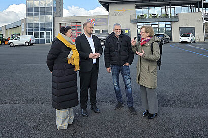 Vier Personen stehen auf einem Flugplatz zusammen und unterhalten sich