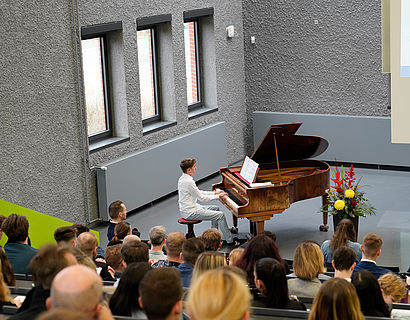 Junge am Klavier beim Vortragen eines Stückes bei der feierlichen Verabschiedung der Absolventinnen und Absolventen 2023 des Fachbereichs WIR