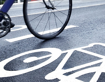 Asphaltierte Straße mit Fahrradsymbol und Radfahrenden, die vorbeifahren