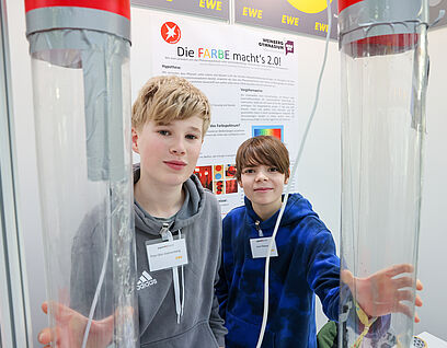 Zwei Kinder halten große zwei große durchsichtige Behälter in die Kamera