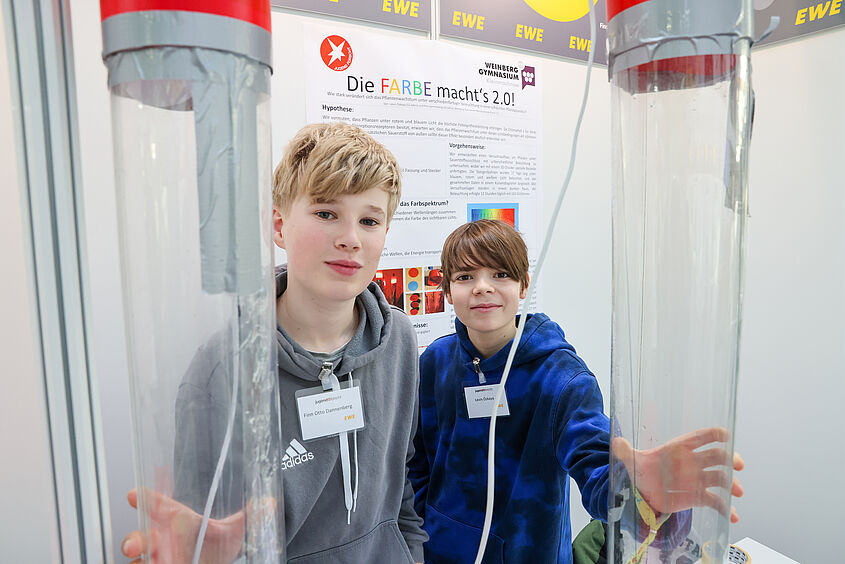 Zwei Kinder halten große zwei große durchsichtige Behälter in die Kamera