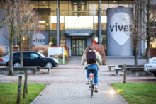 Auf dem Weg zur „Hogeschool“. Studierende der TH Wildau haben ab dem Wintersemester 2024/25 die Möglichkeit, sich für einen belgisch-deutschen Doppelabschluss zu entscheiden. Bild: Copyright VIVES Hogeschool Studierende mit dem Rad auf dem Weg zur VIVE Hogeschool (im Hintergund)