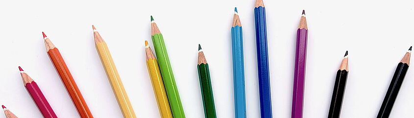 verschiedenfarbige Buntstifte auf weißem Papier