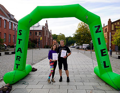 zwei Wander/-innen mit Urkunde an der Zielplattform