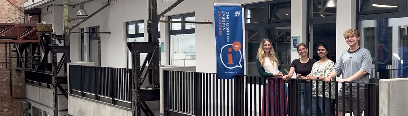 Das team des Infopoint Studienberatung bei einem Fotoshooting vor dem Infopoint in der LOK21