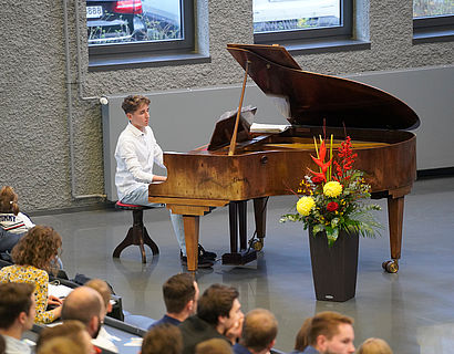 Junge sitzt am Klavier und spielt ein Stück bei der Verabschiedung der Absolventinnen und Absolventen 2023 des Fachbereichs INW