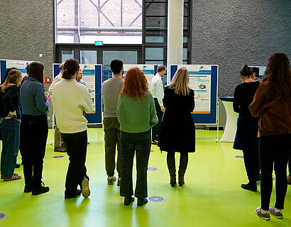 In diesem Bild sind Menschen zu sehen, die sich Posterwände anschauen.