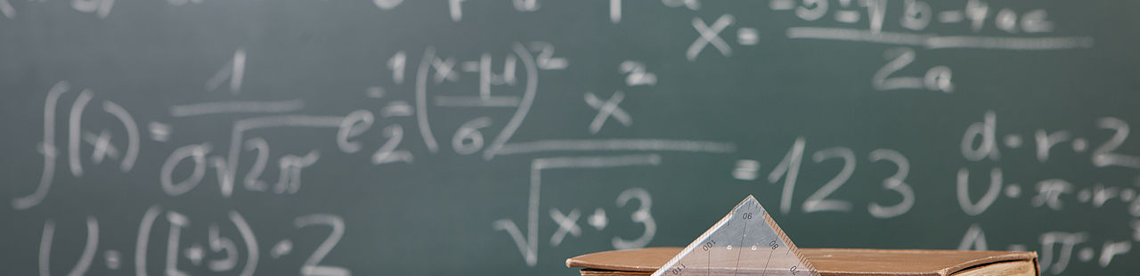 Tafel mit Mathematikformeln und Matheutensilien auf dem Tisch