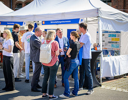 Besucherinnen und Besucher des HIT 2024 der TH Wildau bei einem Gespräch am Stand.