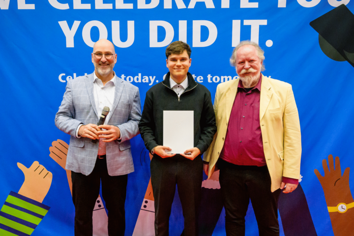 Drei Personen lächeln in Kamera