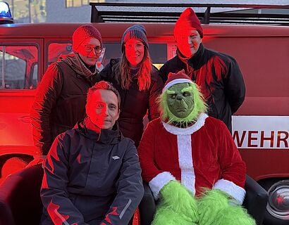 Vier Personen mit einem grünen Anti-Weihnachtsmann