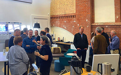 In diesem Foto sind drei kleine Gruppen von Menschen zu sehen, die sich miteinander unterhalten.