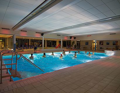 Innenaufnahme des nächtlich beleuchteten Schwimmbeckens im Erlebnisbad Wildorado zeigt eine Gruppe bei einem Aquasport-Kurs.