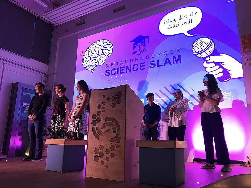 Science Slam 2026. Bühnenbild mit Menschen