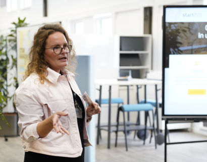 Eine Frau hält einen Vortrag, neben ihr ein Display