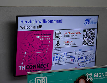 Screen mit Infos zur THCONNECT 2025 in einem Gebäude der TH Wildau