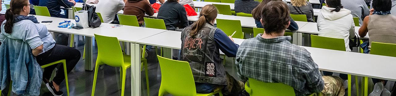 Sitzende Studierende im Vorlesungsraum, fotografiert von hinten
