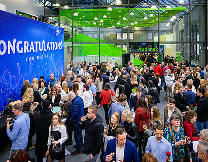 Absolvent*innen und Gäste bei der Verabschiedung 2025 im Foyer von Halle 17 
