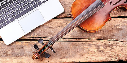 Laptop und Geige auf Holztisch