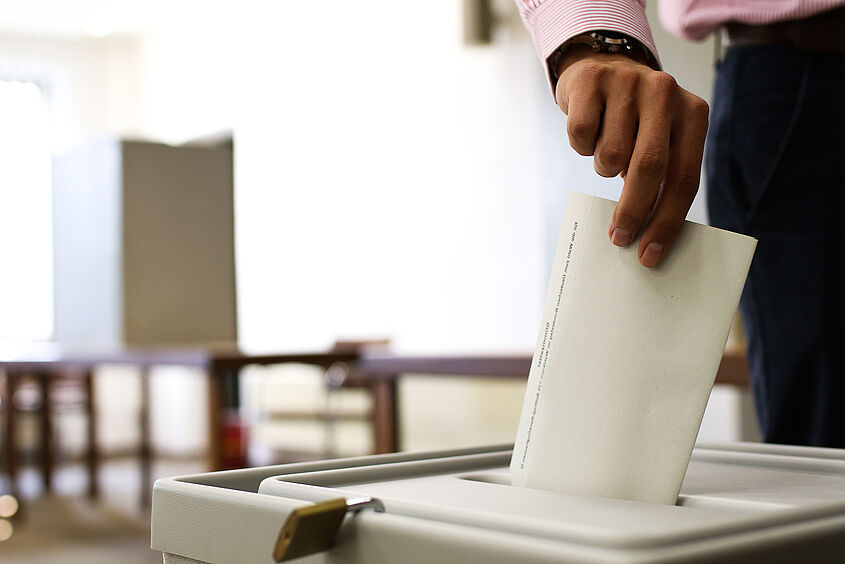 Wahl Person steckt Zettel in Wahlurne
