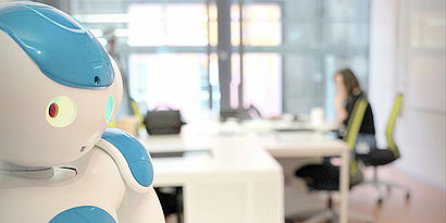 Humanoider Roboter vor Schreibtisch mit Person