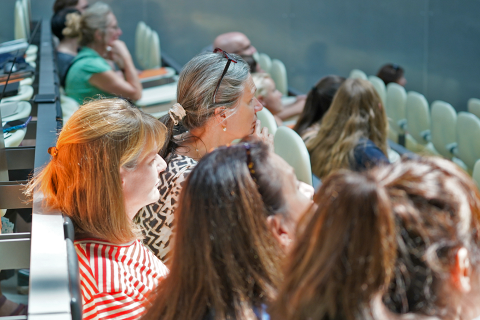 Personen sitzen in Stuhlreihen in einem Hörsaal