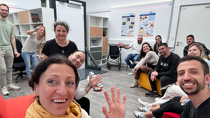 Gruppe von Menschen winkt bei einem Selfie in die Kamera