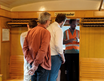 Menschen stehen in der Führerkabine und im Waggon einer historischen S-Bahn
