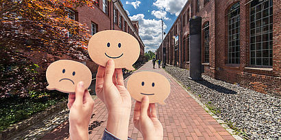 Collage aus TH-Wildau-Bild und Händen, die Smileys hochhalten