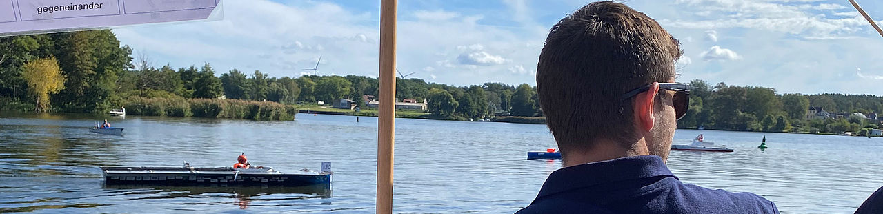 Teilnehmer blickt auf das Wasser und ist von hinten zu sehen