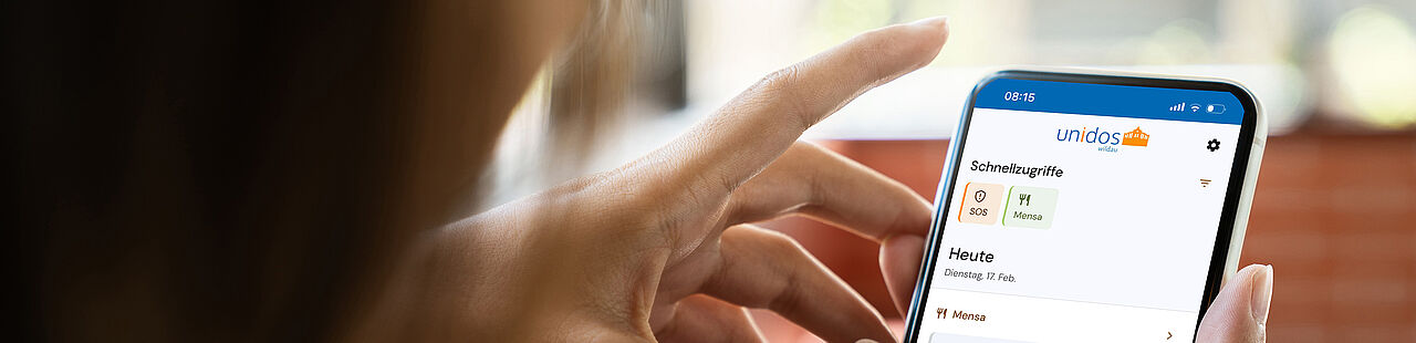 Schulterblick bei einer Frau, die ein Smartphone in der Hand hält, auf dem Screen ist die Unidos App zu sehen