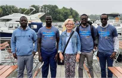 Eine Gruppe von Personen steht auf einem Bootssteg und präsentiert ihre Veranstaltungs-T-Shirts der Solarboot-Regatta.