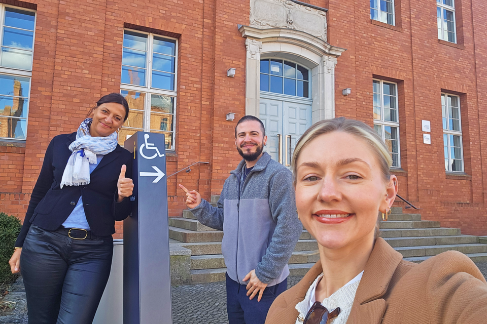 Drei Personen an einem Wegweiser