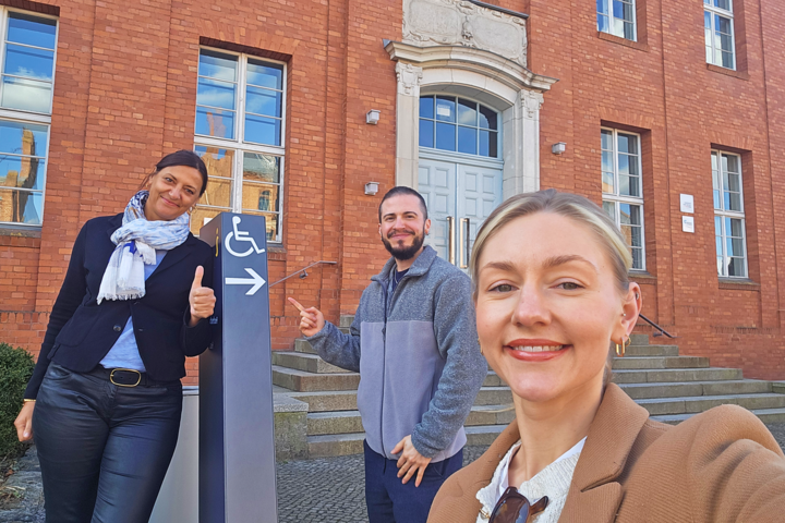 Drei Personen an einem Wegweiser