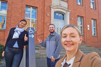 Drei Personen an einem Wegweiser