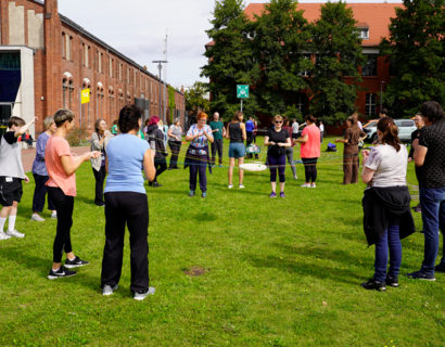 Gruppe spielt Balance-Spiel auf Wiese