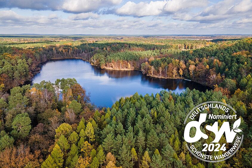 Der Paul-Gerhardt-Weg von Berlin nach Lübben durch das Dahme-Seenland ist als einziger Wanderweg Brandenburgs für den Titel „Deutschlands schönster Wanderweg 2024“ nominiert. (Bild: Michael Zalewski / Landkreis Dahme-Spreewald) Der Paul-Gerhardt-Weg von Berlin nach Lübben durch das Dahme-Seenland, Luftbild mit Seenlandschaft und Logo