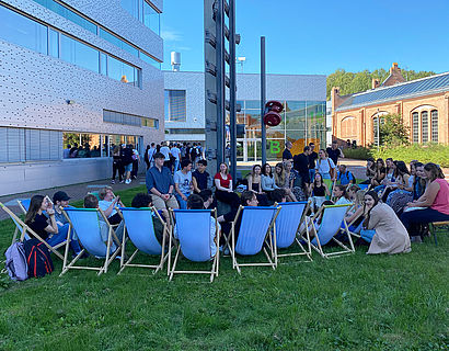 Erstsemester-Studierende in lockerer Gesprächssituation auf der Wiese zwischen Haus 16 und Halle 17