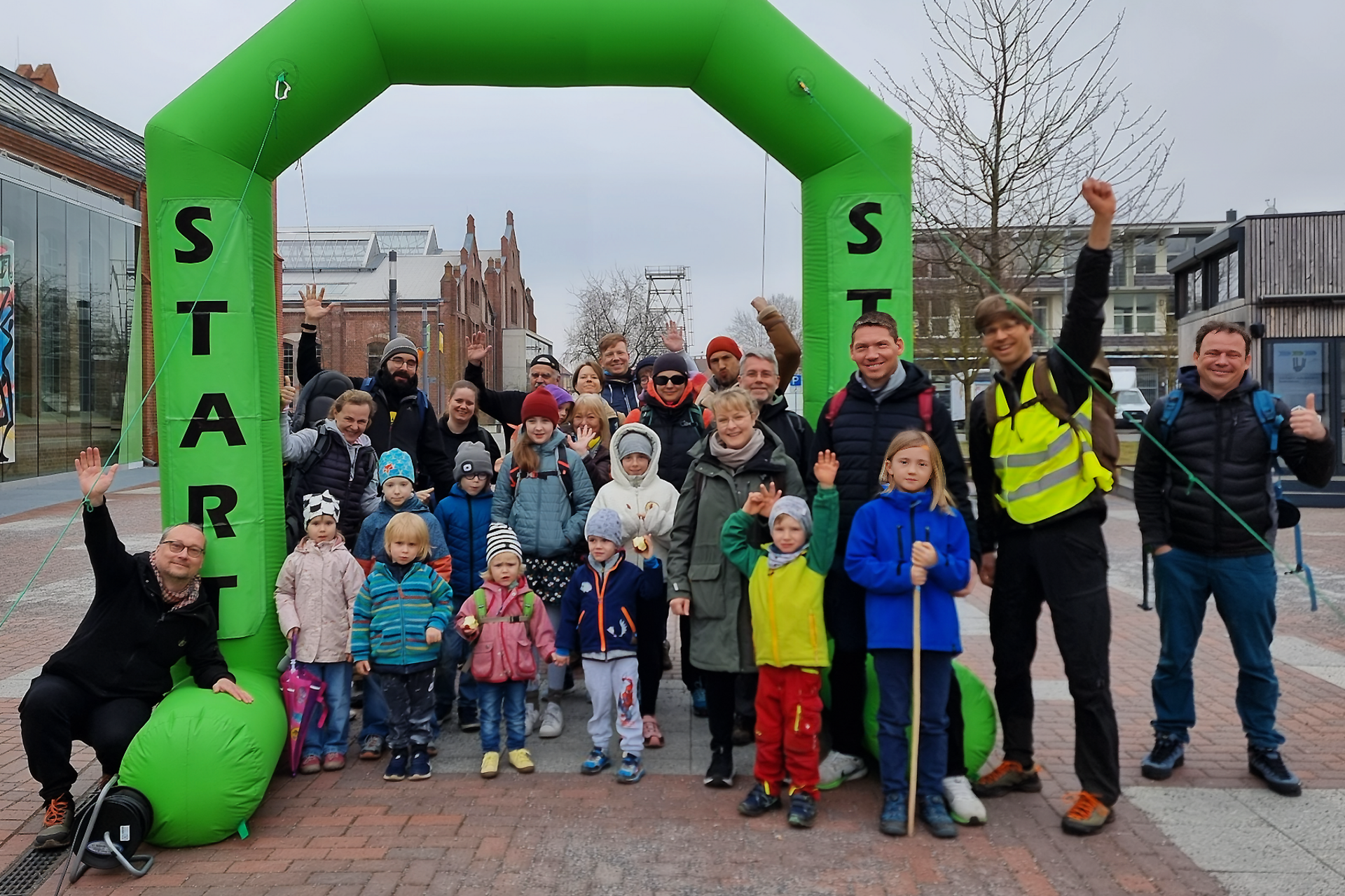 Mini Gruppenbild Kleeblattwanderung Personen und Kinder stehen unter einem Bogen mit der Aufschrift Start