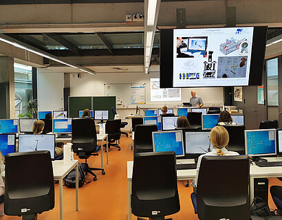 Studieninteressierte an PC-Tischen in einem Seminarraum