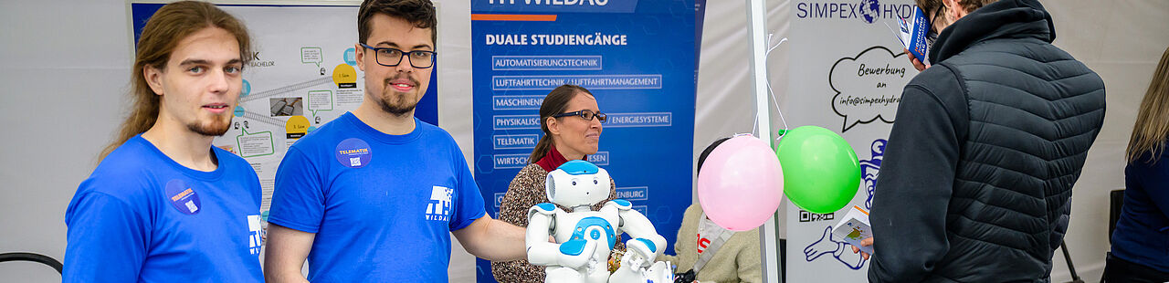 Studierende an einem Stand mit einem humanoiden Roboter beim HIT 2025