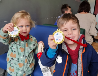 Zwei Kinder halten Medaillen in die Kamera