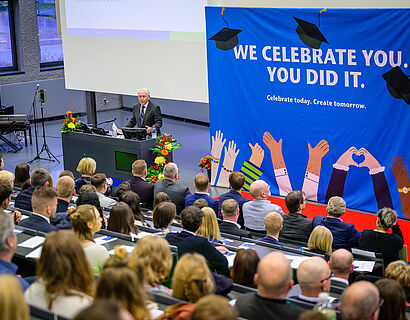 Blick von hinten auf die Teilnehmenden der Verabschiedung der Absolvent*innen 2024/2025 im Audimax