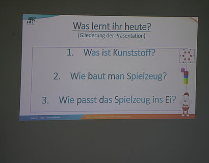 Kinderuni Winter Edition 2024  - Beamerfolie mit Fragen, wie das Spielzeug ins Ü-Ei kommt