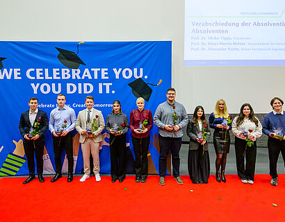 Absolvent*innen stehen in einer Reihe für ein Gruppenbild nach der Gratulation